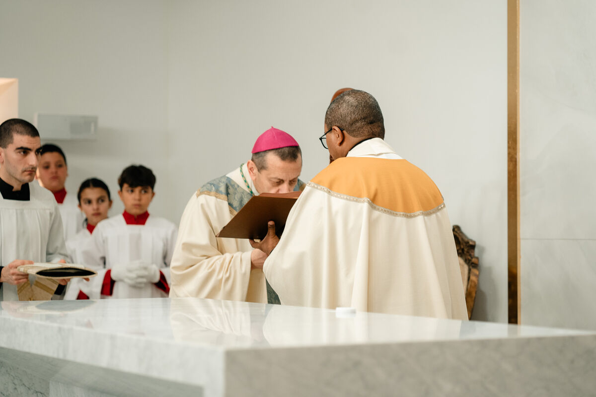 Bishop kisses the Book of the Gospels with altar servers behind