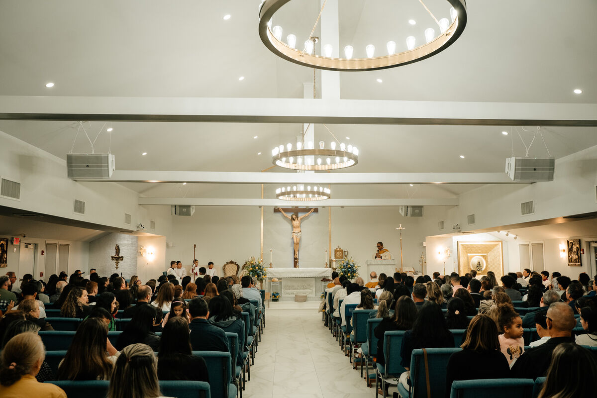 The interior of the sanctuary at Our Lady of Aparecida during Mass, with the congregation gathered before the central crucifix