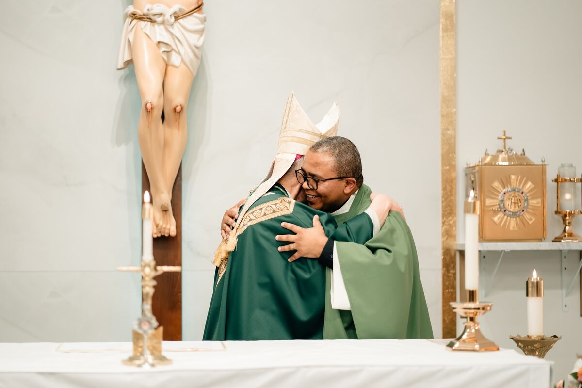 Two priests embrace at the altar after Mass