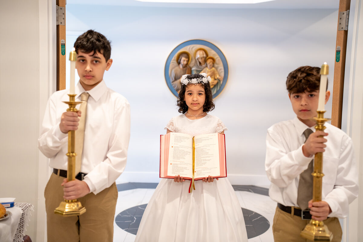 First Communion procession with children carrying candles and the Book of the Gospels at Our Lady of Aparecida