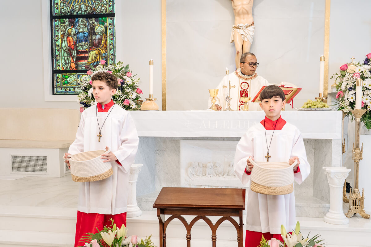 Altar servers in red cassocks holding baskets for the offertory