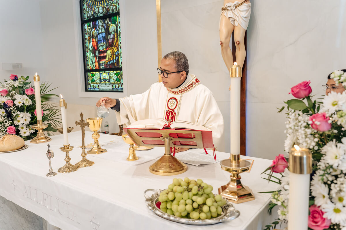 Priest pours water into the chalice at the altar