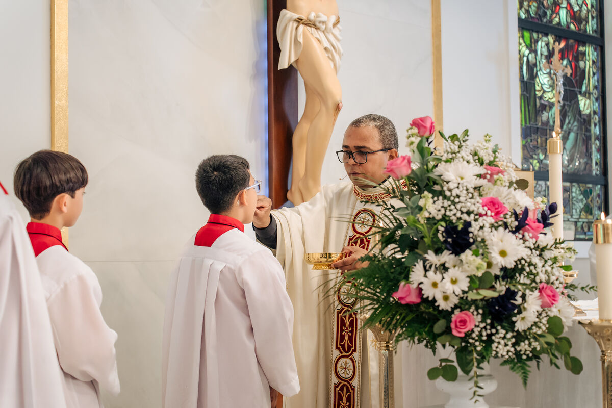 Priest distributes Holy Communion with a server at his side