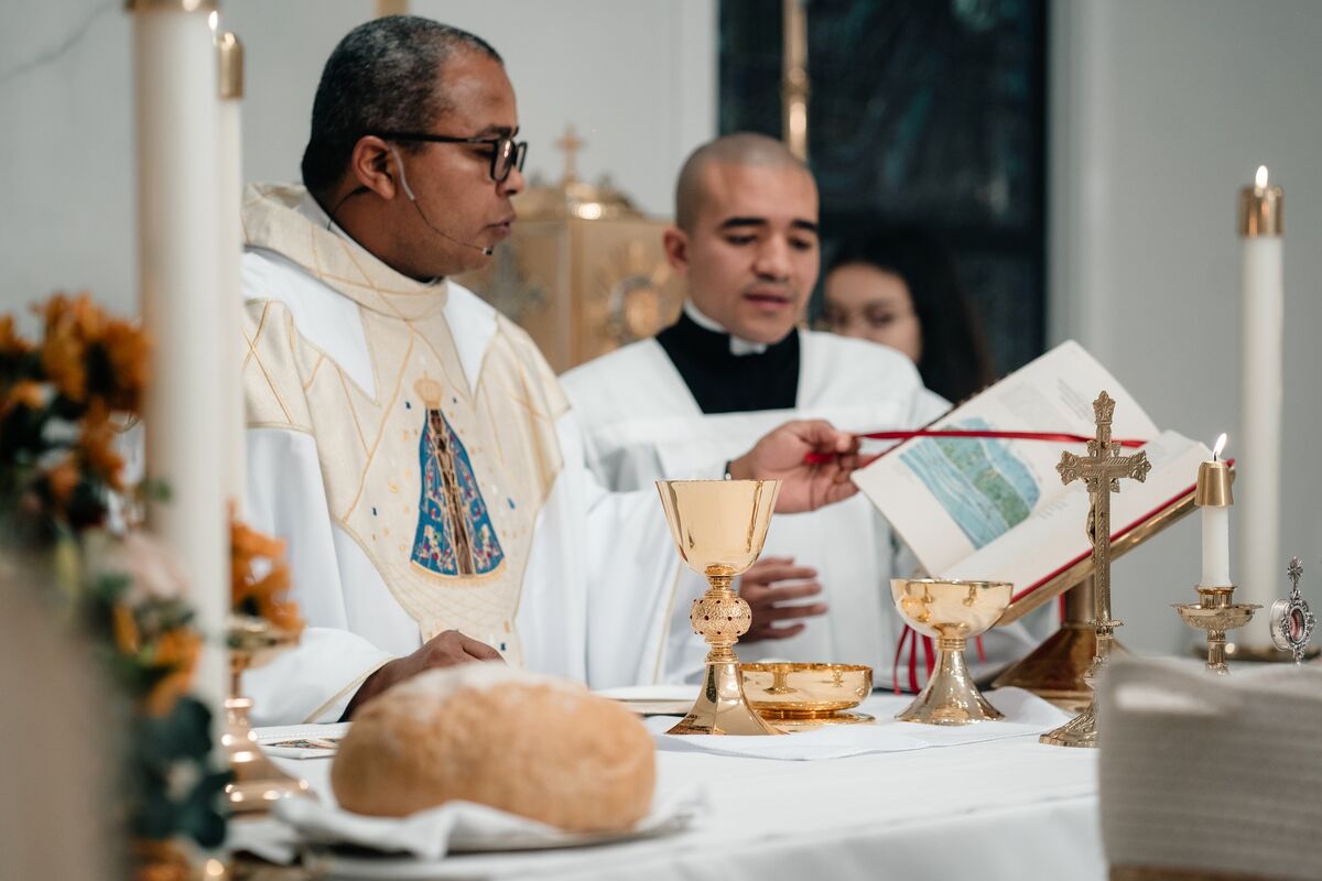 Priest at the altar with a server marking the Missal