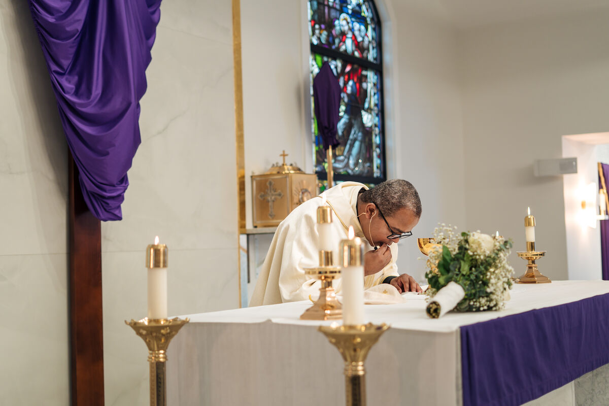 Priest bowed in prayer at the altar during Lent